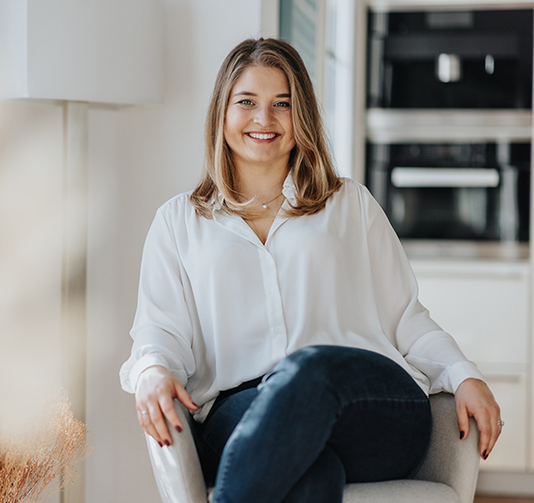 Das Bild zeigt die Coachin lässig auf einem Stuhl sitzend.